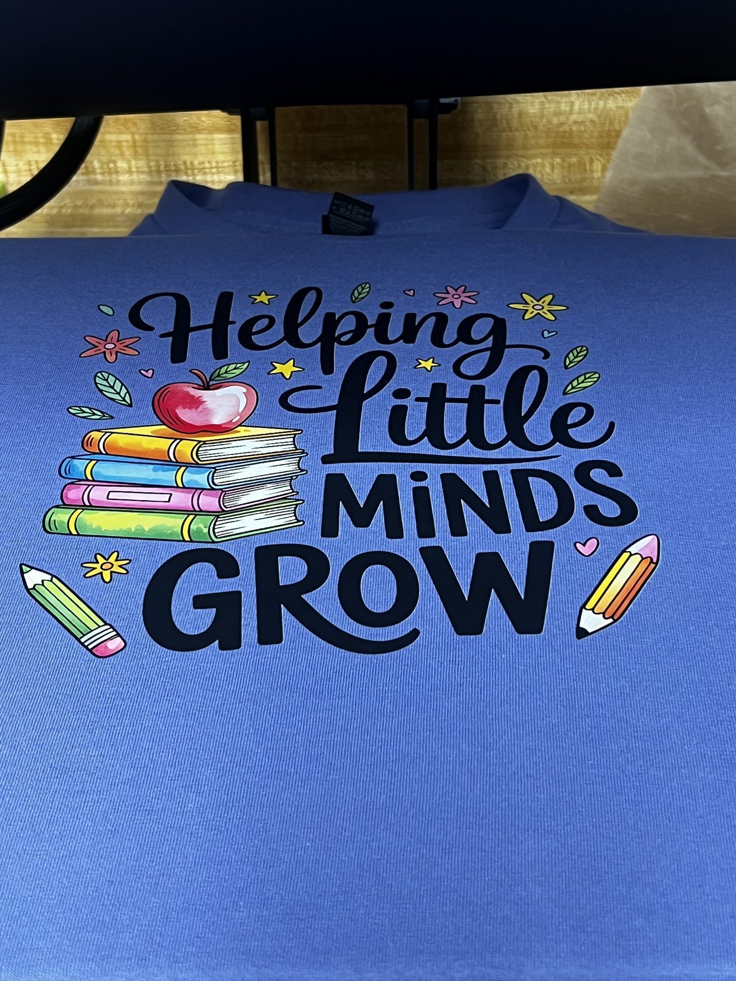 Custom blue shirt with Helping Little Minds Grow pencil and book design